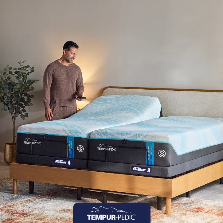 Tempur-Pedic mattress in a minimal, modern bedroom with one person sitting on the bed, promoting a $300 instant gift toward a total sleep solution.